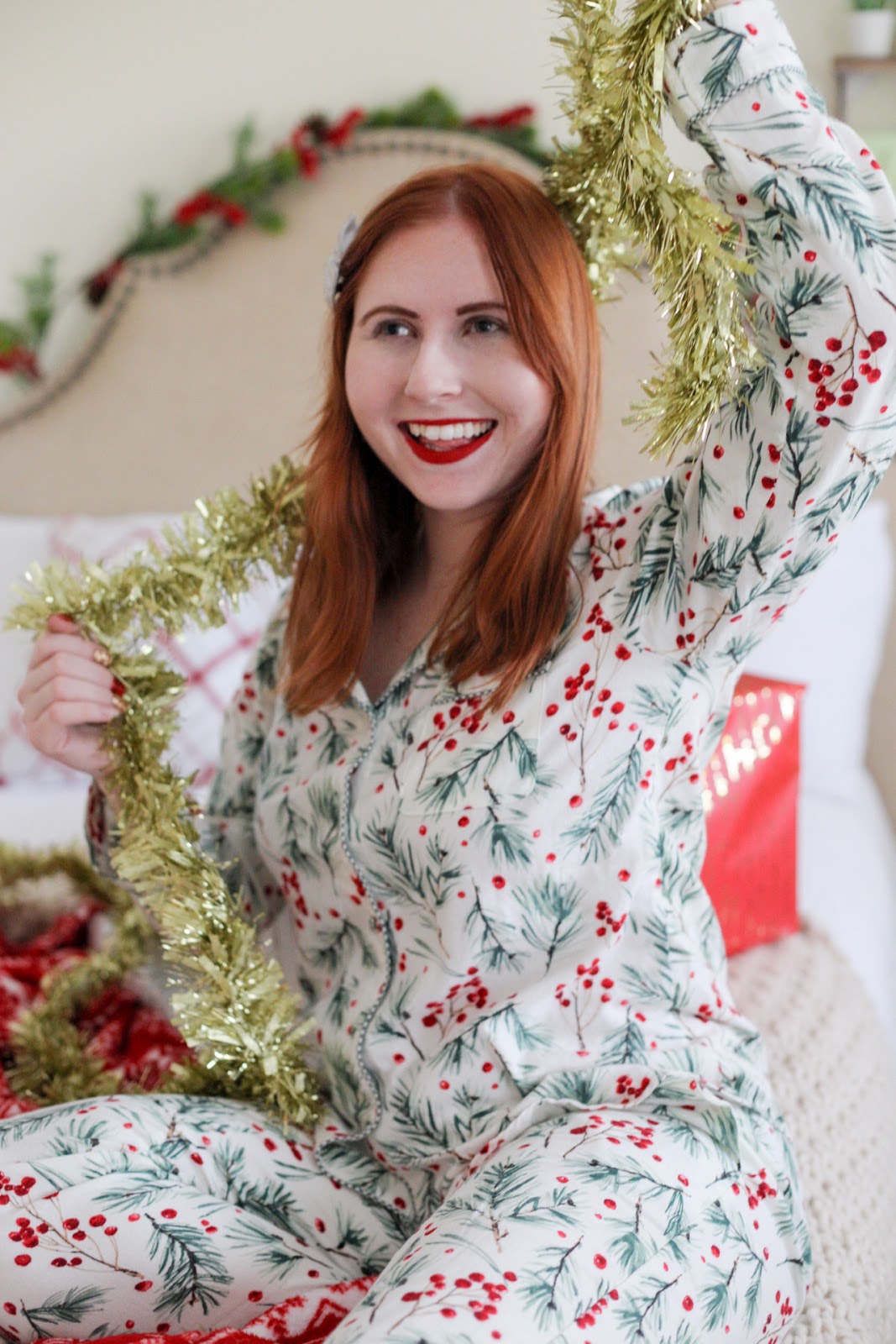 Affordable by Amanda, Tampa Style Blogger Sharing Festive Matching Christmas Pajamas Under $30 For the Holiday Season. She is wearing a pair of holly printed pajamas from stars above collection at Target.