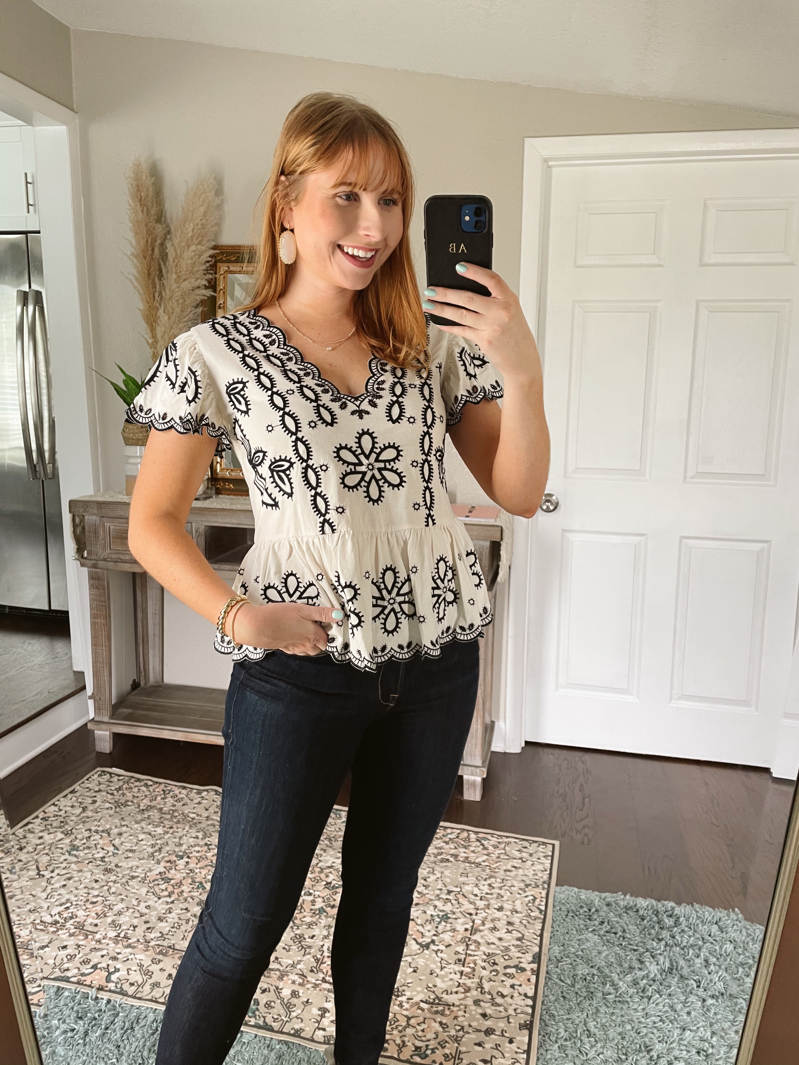 Amanda Burrows wears a white and navy Eyelet Lace Scalloped Trim Peplum Top with dark denim jeans. 