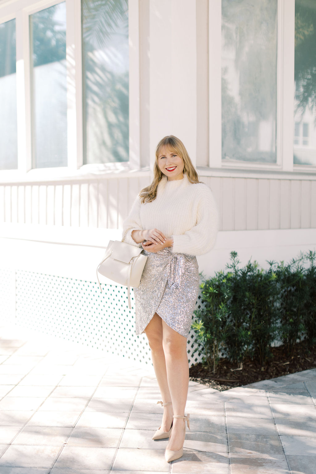 New Years Eve Outfit Ideas 2021. What to Wear for a New Years Eve Party. Affordable by Amanda wears a cozy white sweater with a silver sequin mini skirt and nude heels.