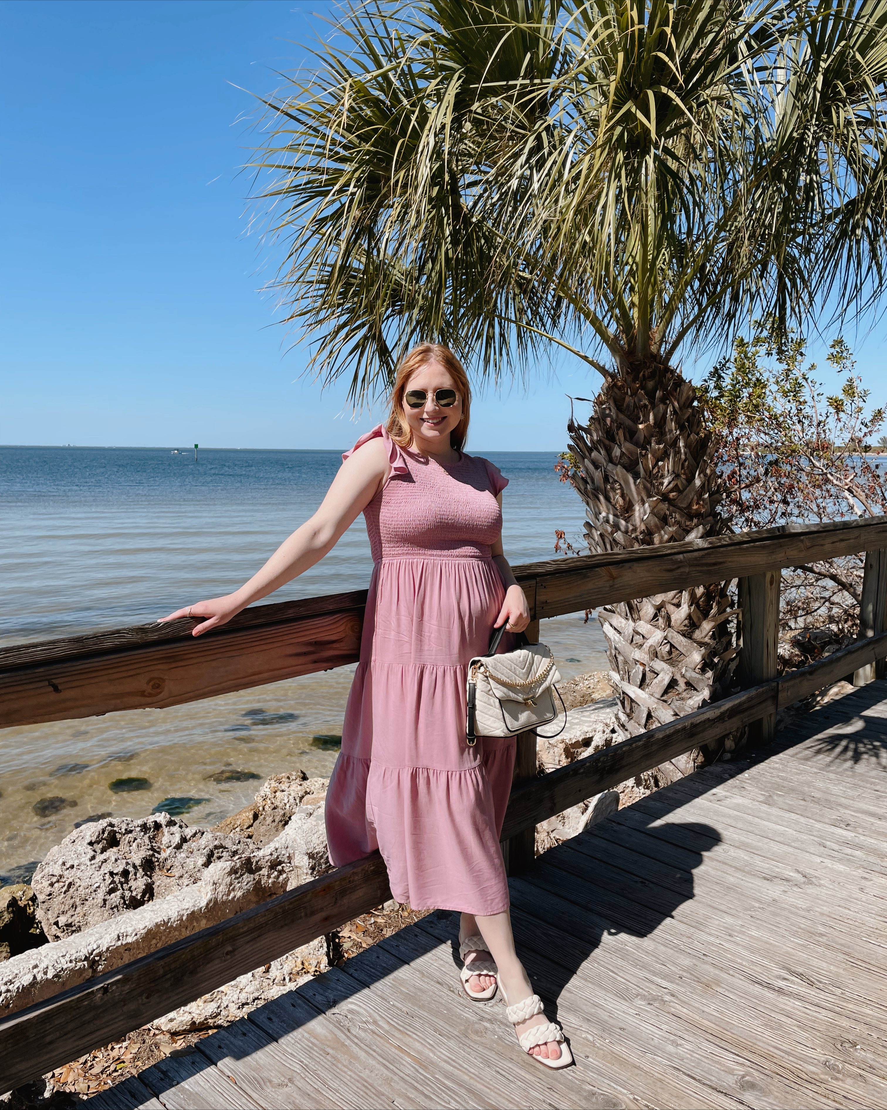 Affordable by Amanda wears long purple tiered maxi dress from Amazon with white braided sandals holding a chevron quilted satchel by the beach boardwalk.