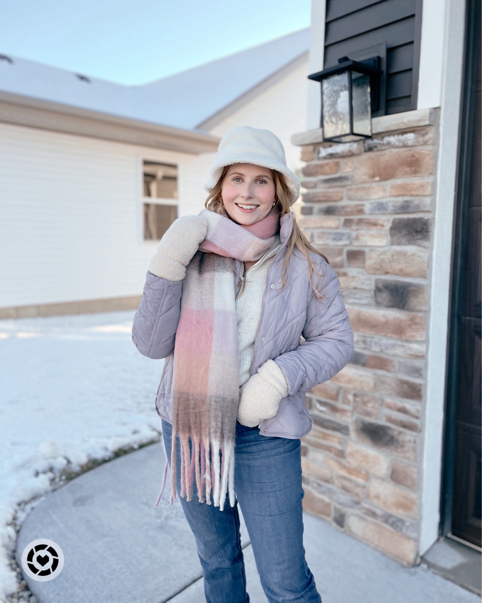 Affordable by Amanda wears a purple puffer jacket, white sherpa bucket hat, plaid scarf, jeans, and sorel winter boots