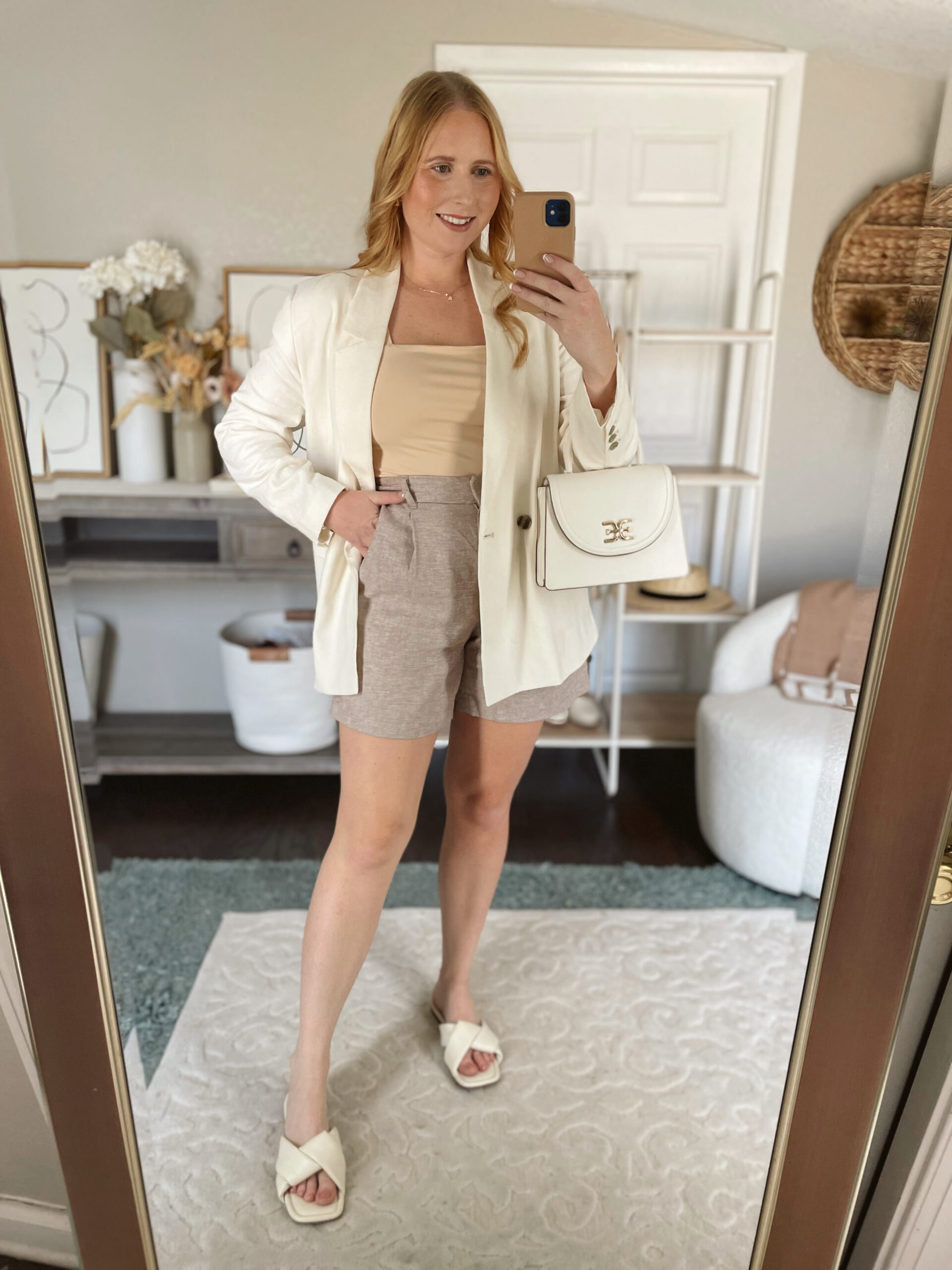 Affordable by Amanda wears a linen blazer with neutral tailored shorts and puffy slide sandals as a summer outfit idea